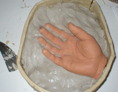 You'll need to build up a wall of waterbased clay around the hand to mark it in half. You'll need to build up a wall of waterbased clay around the hand to mark it in half.
